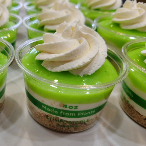 Lime dessert jars topped with whipped cream and lime zest, with a whole lime in the foreground.
