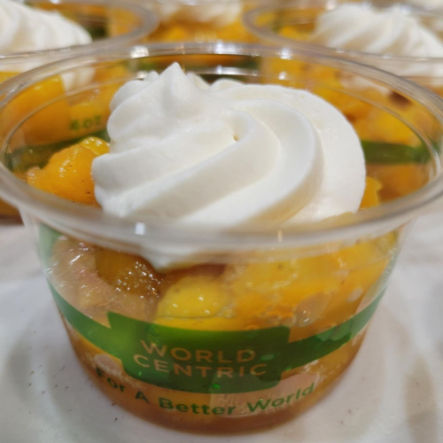 Bowl of fruit dessert topped with glossy orange peach sauce