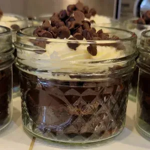 Chocolate dessert in a clear glass jar topped with whipped cream and chocolate chips