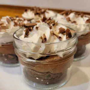 Glass dessert cups with chocolate mousse and whipped cream, topped with chocolate shavings