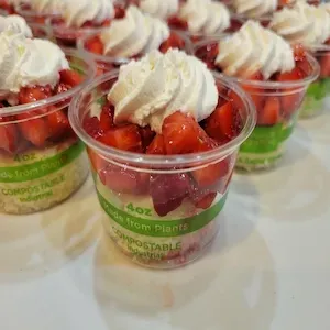 Clear plastic dessert cup labeled “Strawberry Shortcake” on a red surface