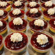 Rows of small dessert cups with red jelly and whipped cream topping