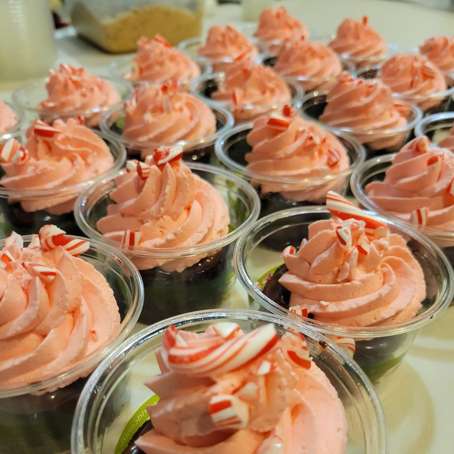 Rows of clear cups filled with pink swirled frosting topped with white and red sprinkles
