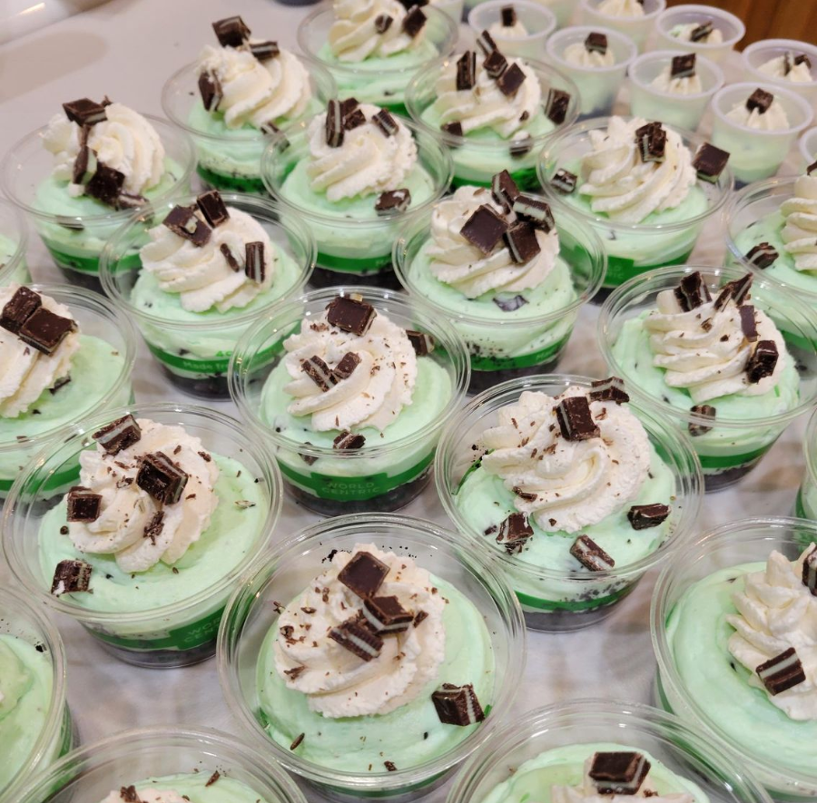 Trays of layered green dessert cups topped with whipped cream and chocolate shavings