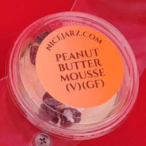 Clear plastic dessert cup labeled “Peanut Butter Mousse (V)(GF)” on a red background