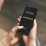 Hands holding a smartphone showing a 5-star feedback screen on a dark background