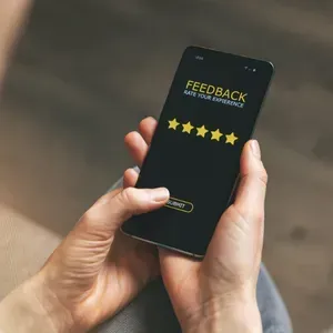 Hands holding a smartphone showing a 5-star feedback screen on a dark background