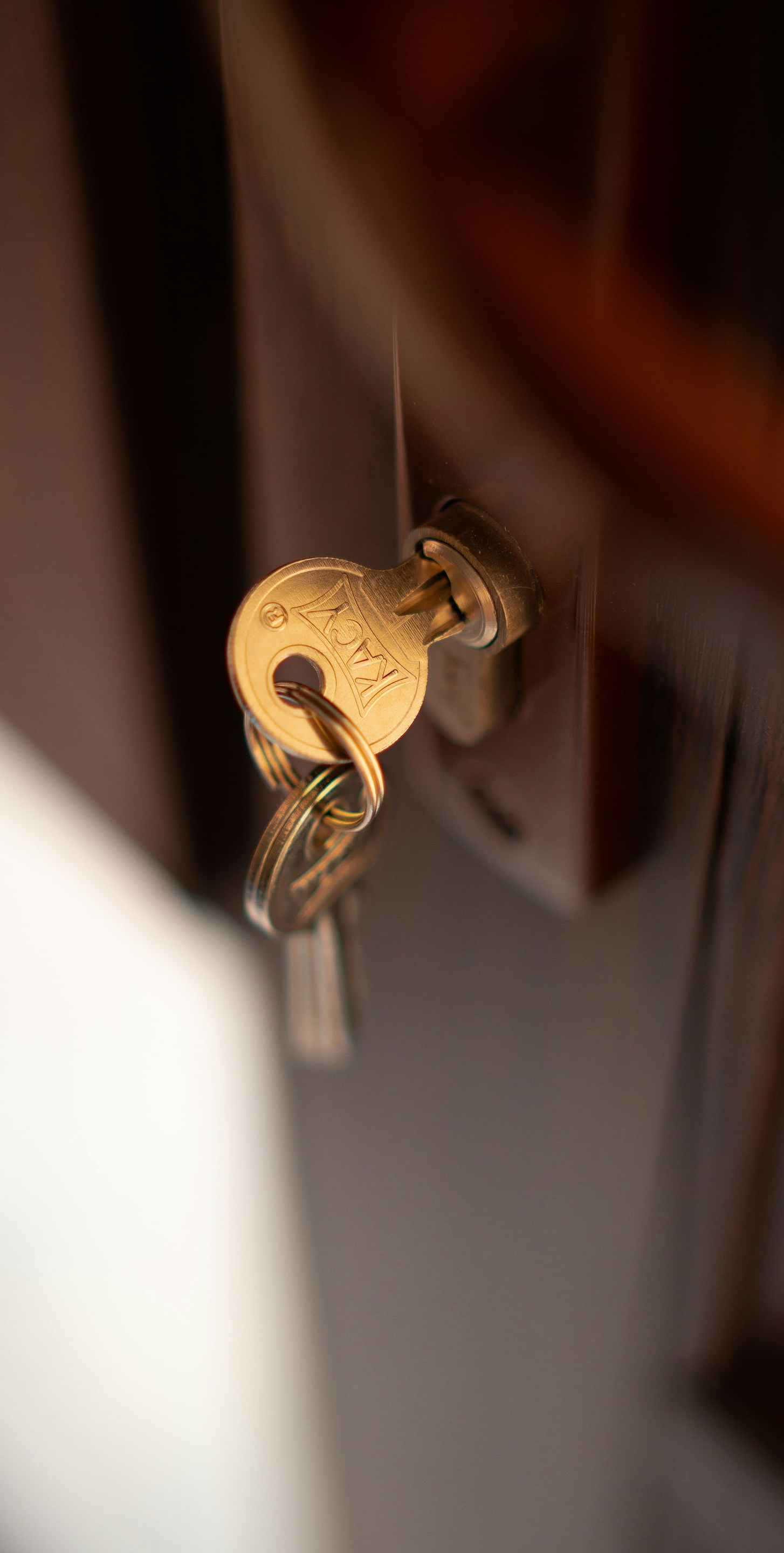 Close-up of brass keys in a lock on a dark wooden door