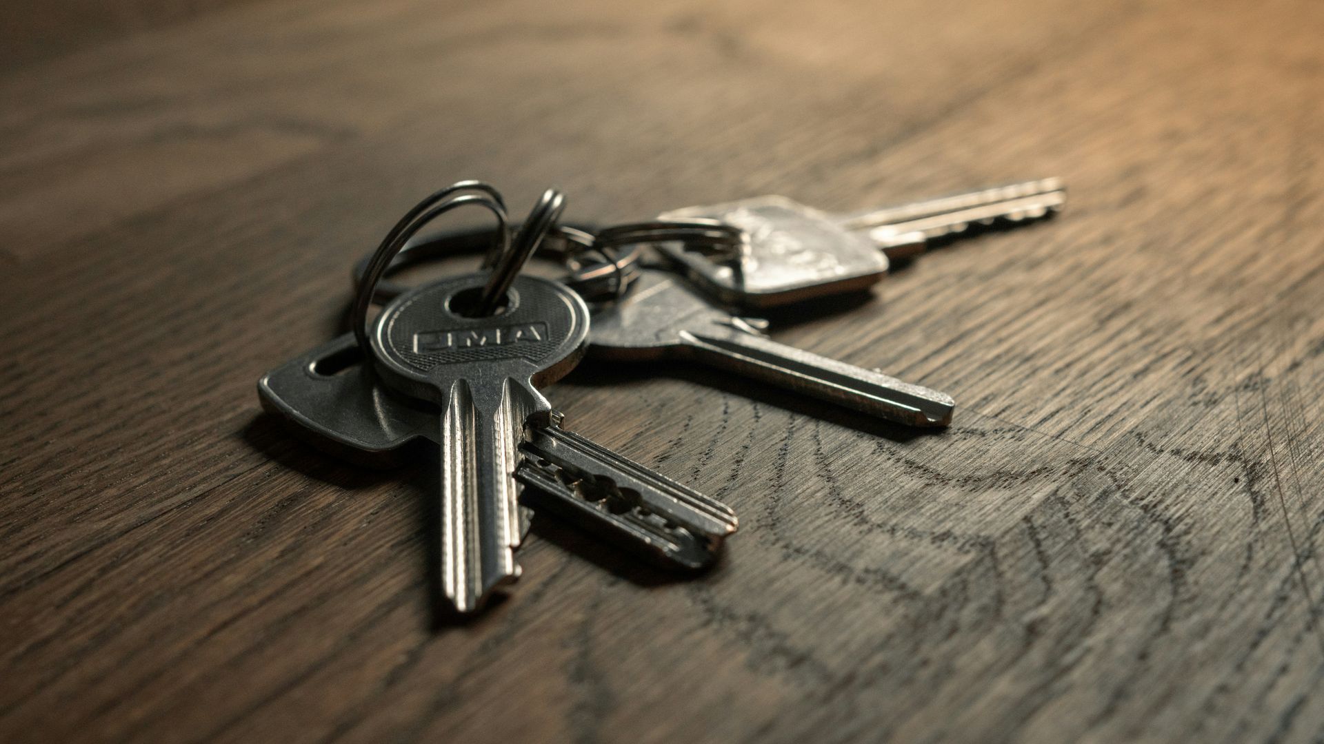 A small keyring with several silver keys resting on a wooden surface.