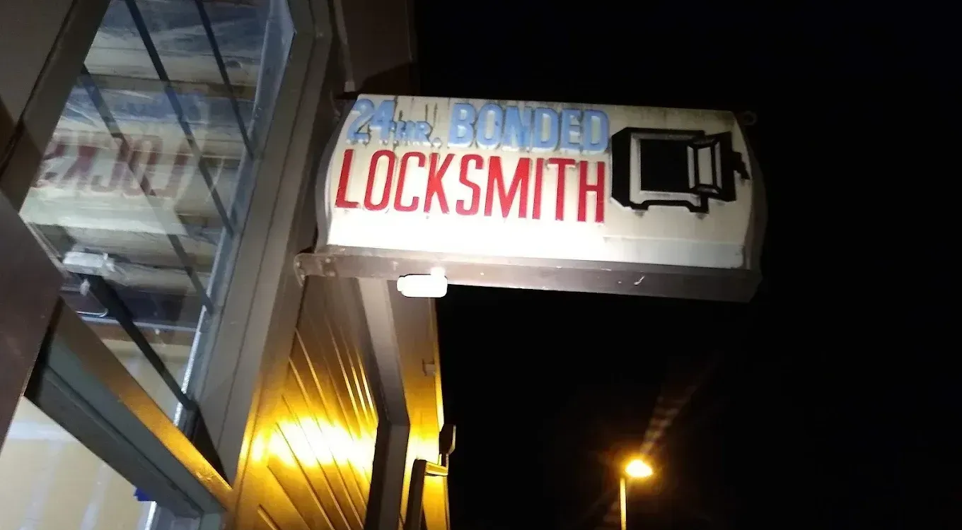 Neon locksmith sign on a storefront at night, lit against a dark sky.