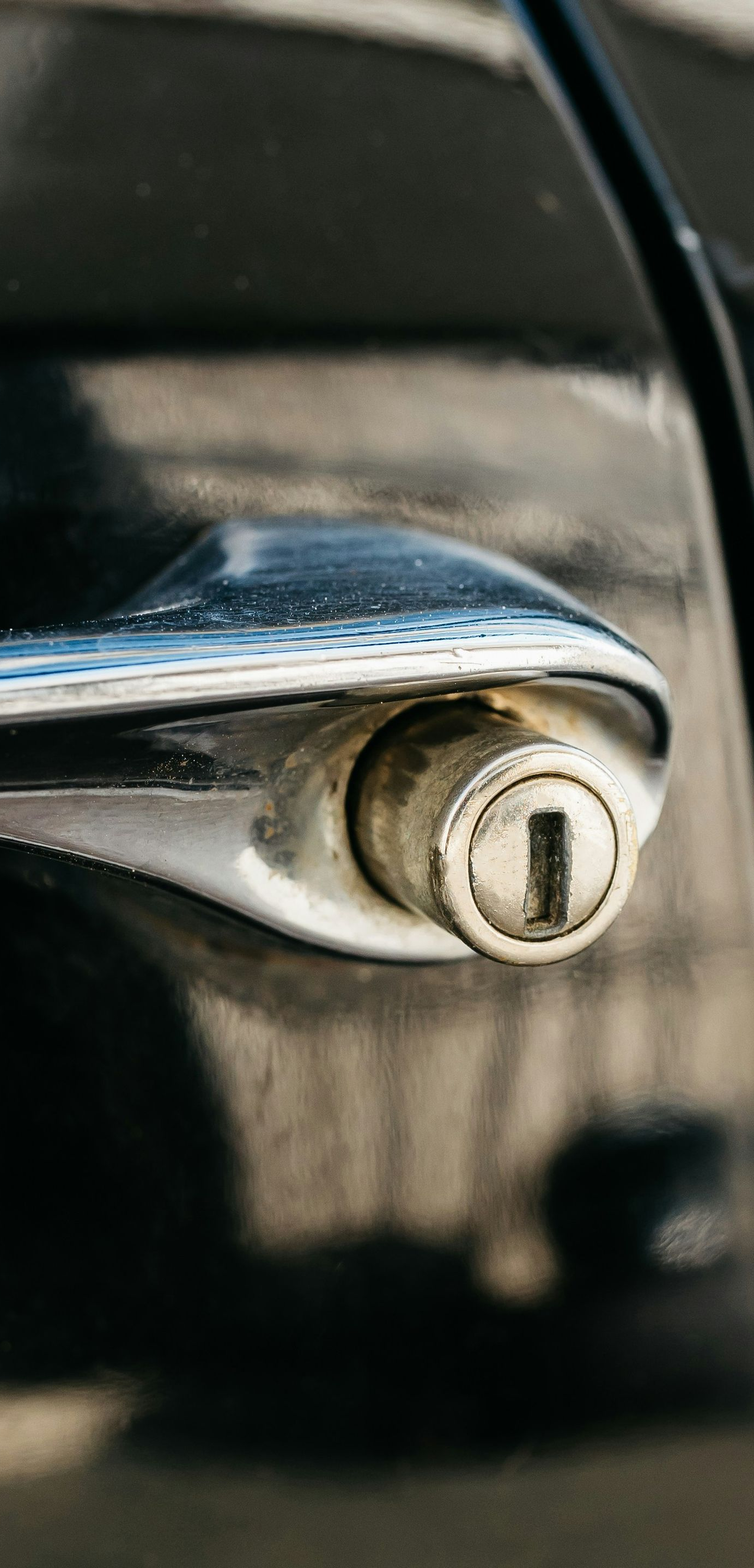 Close-up of a silver car door lock on a black vehicle