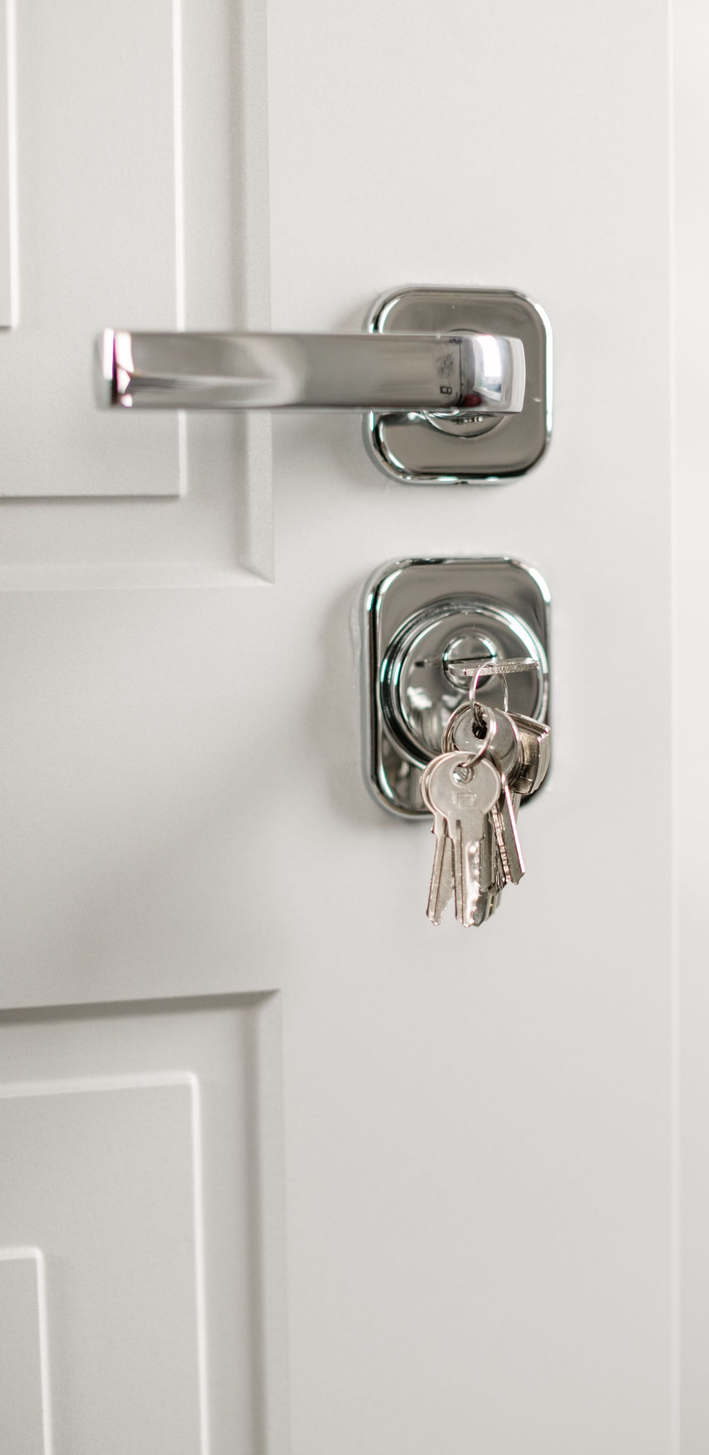 Silver deadbolt lock with key in a white door