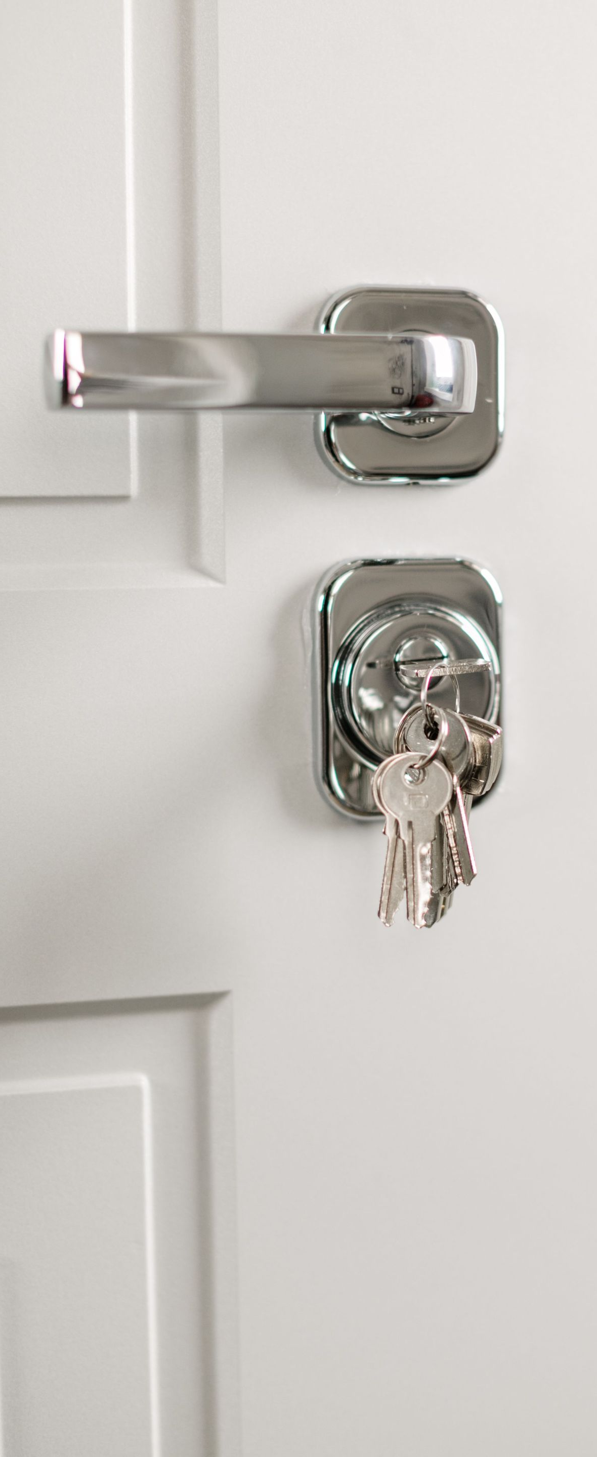 White door with a silver latch and a key inserted in the lock.