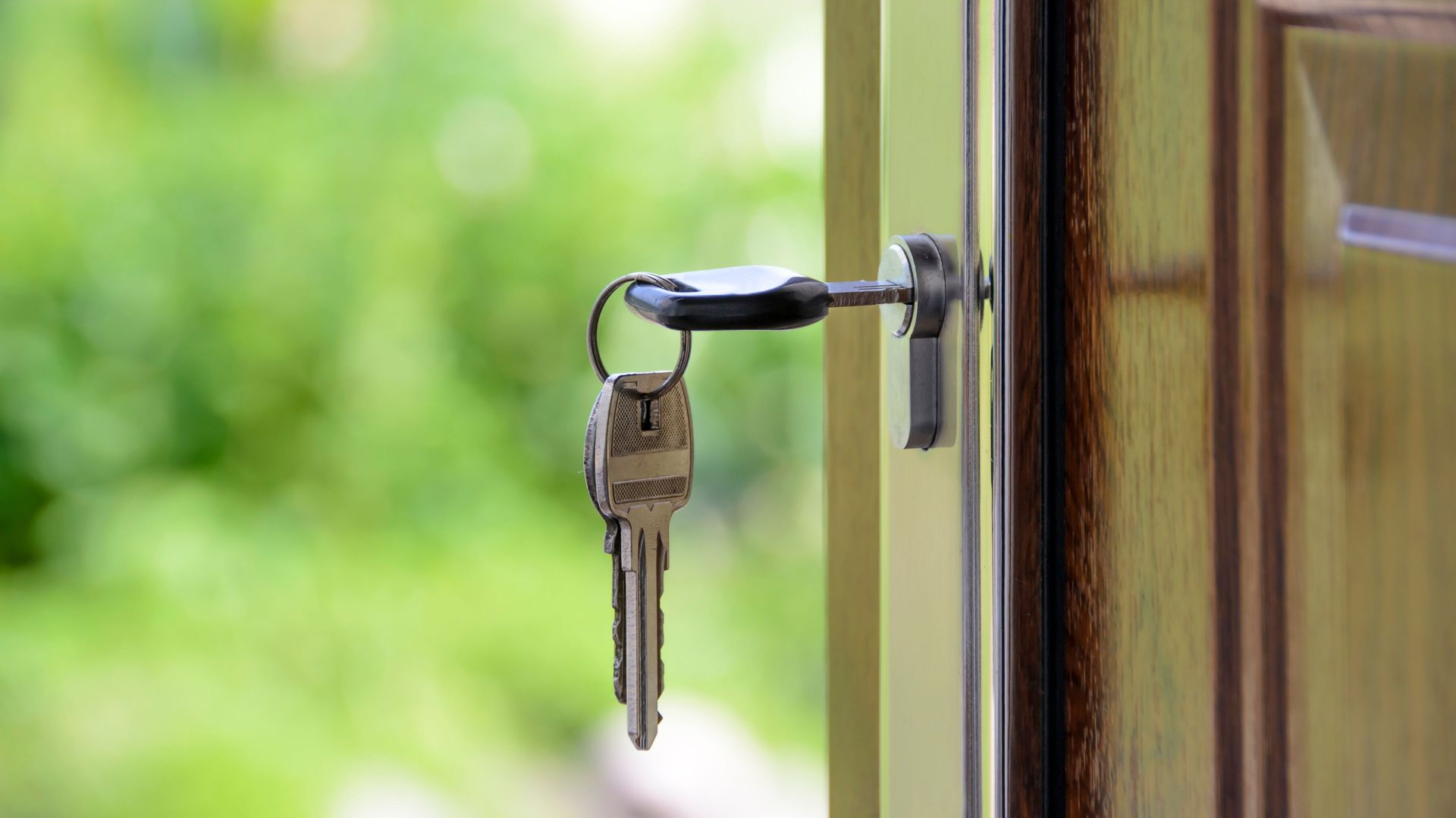 Keys hanging in a front door lock with the door slightly open