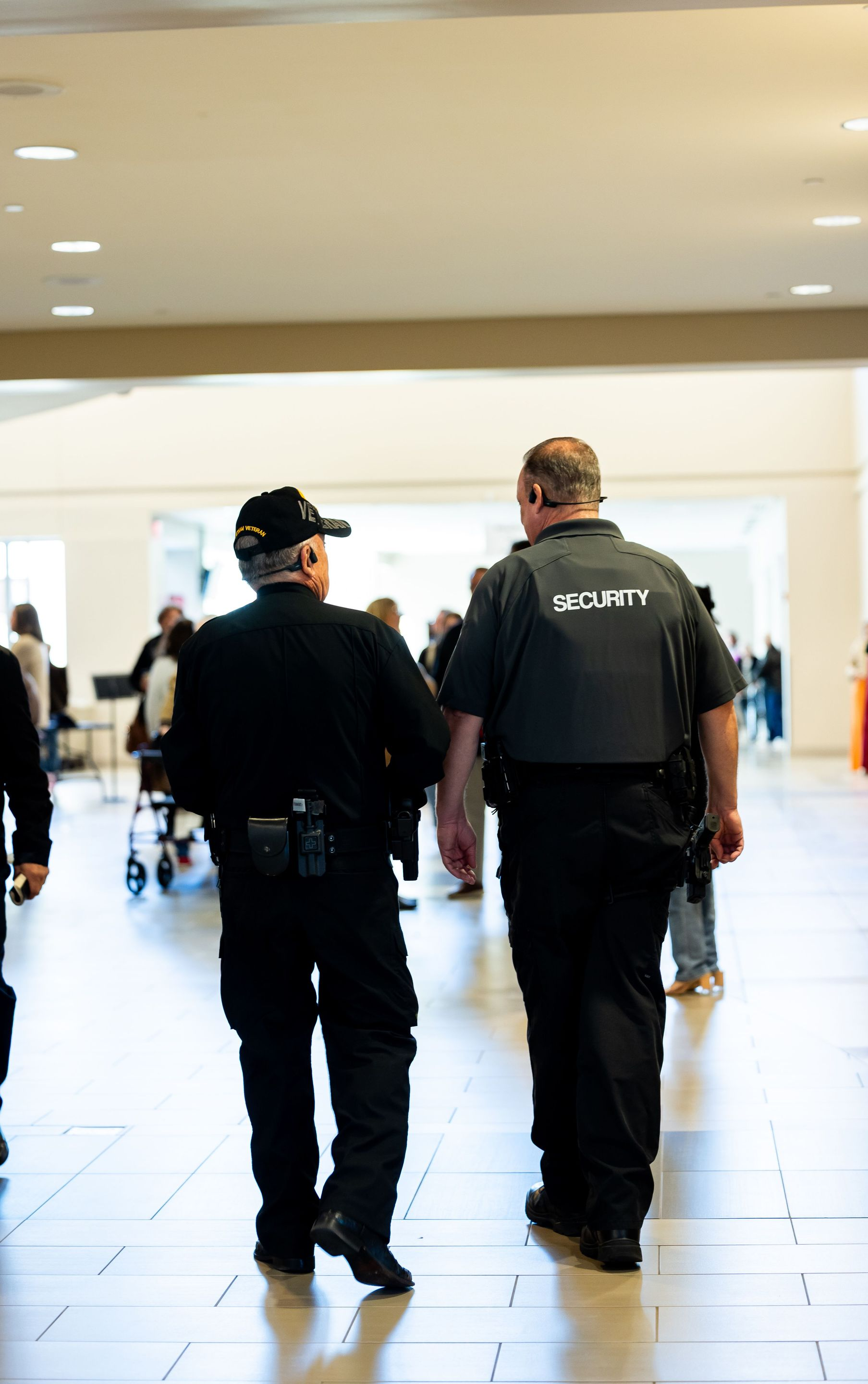 Two security guards walking through a bright indoor hallway