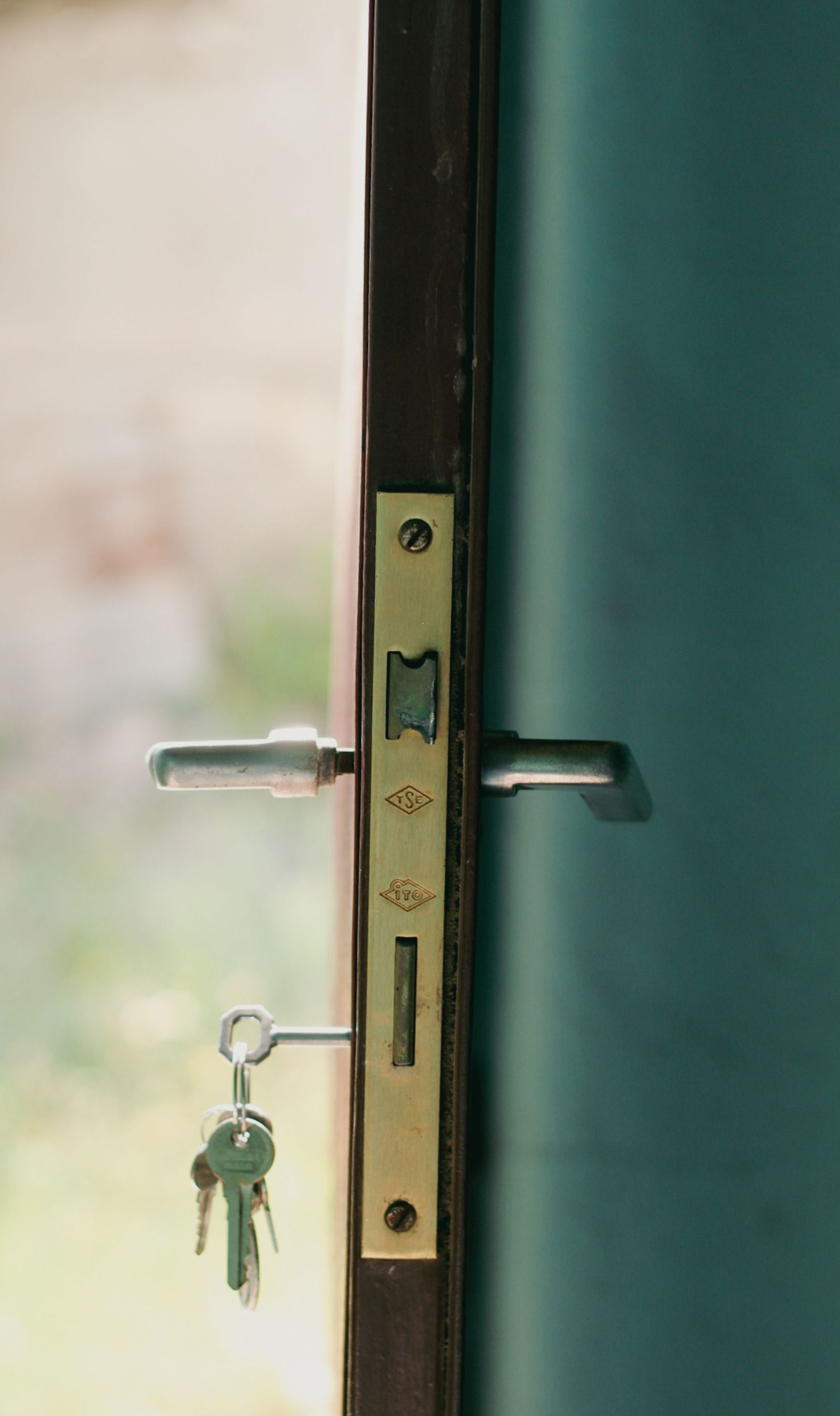Close-up of a door lock with a key inserted and keys hanging from the latch