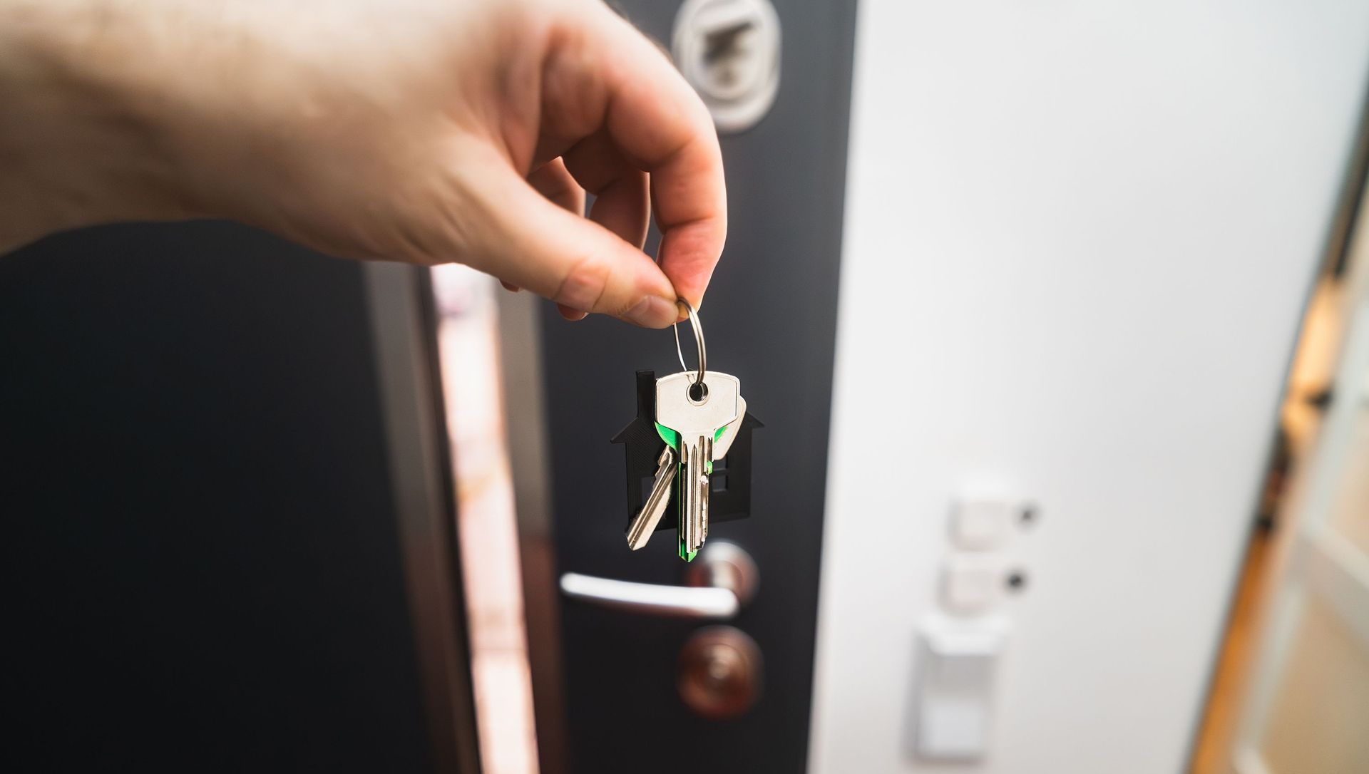 Hand holding keys near a front door lock