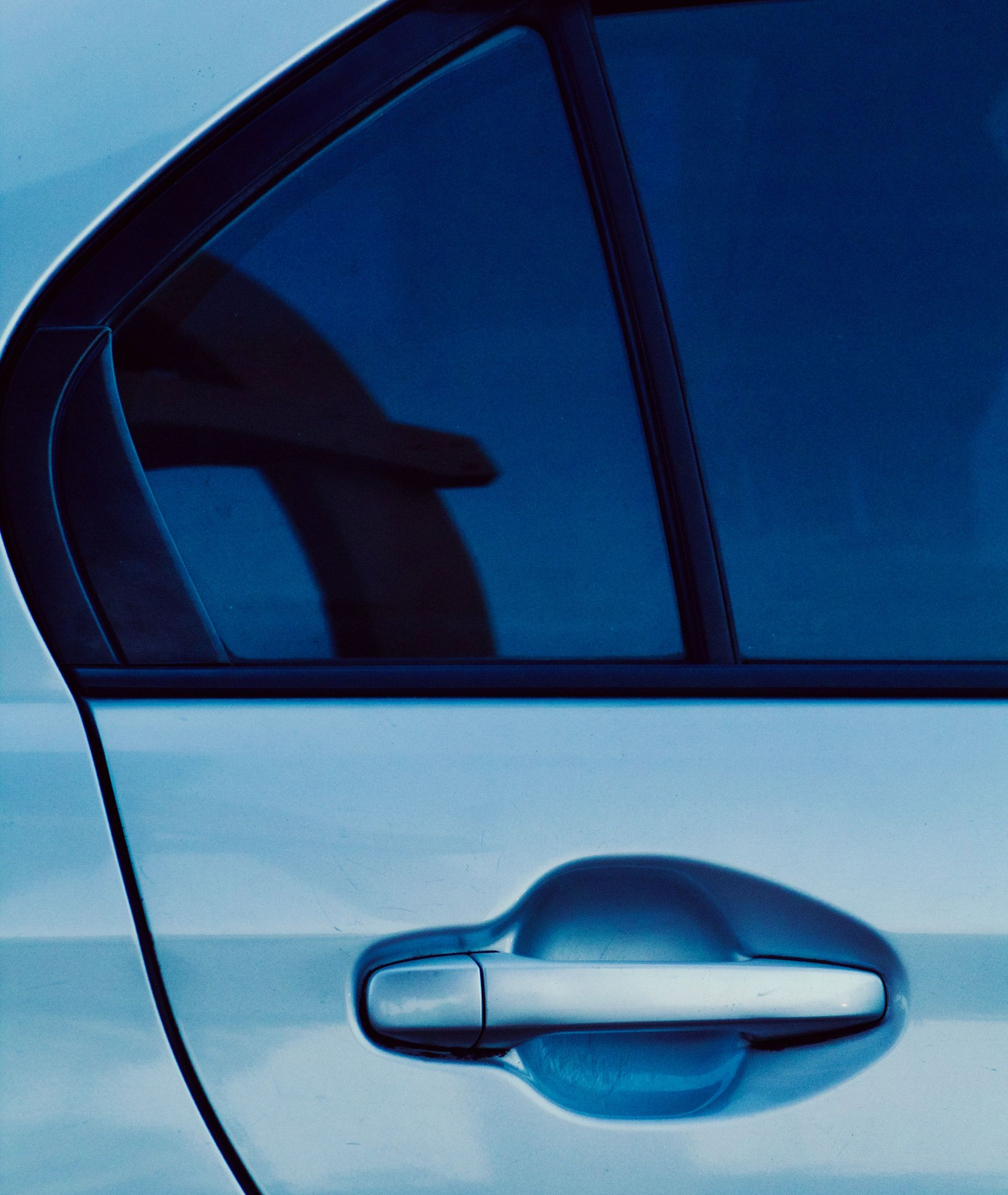 Close-up of a silver car door with tinted window and chrome handle