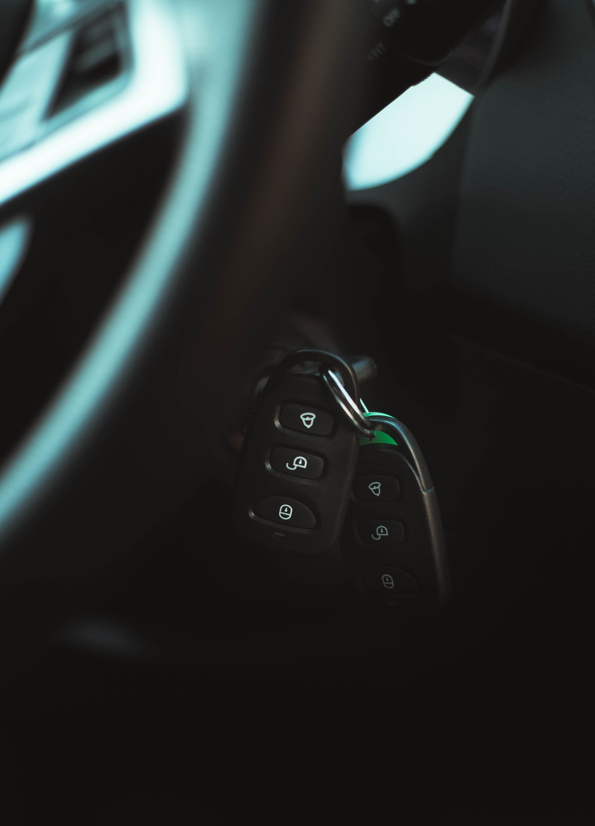 Close-up of a black car key fob hanging inside a dimly lit vehicle
