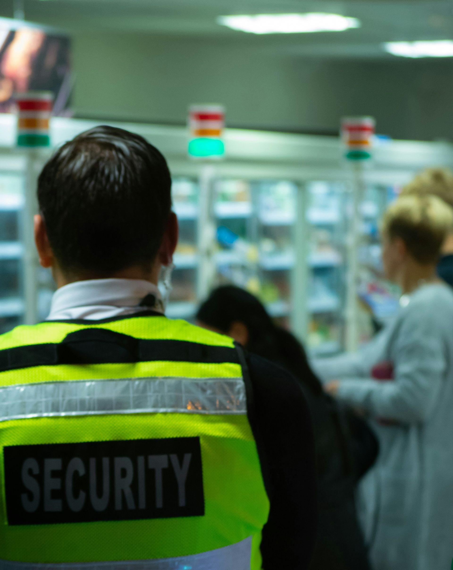 Security guard in neon vest monitoring shoppers in a store aisle