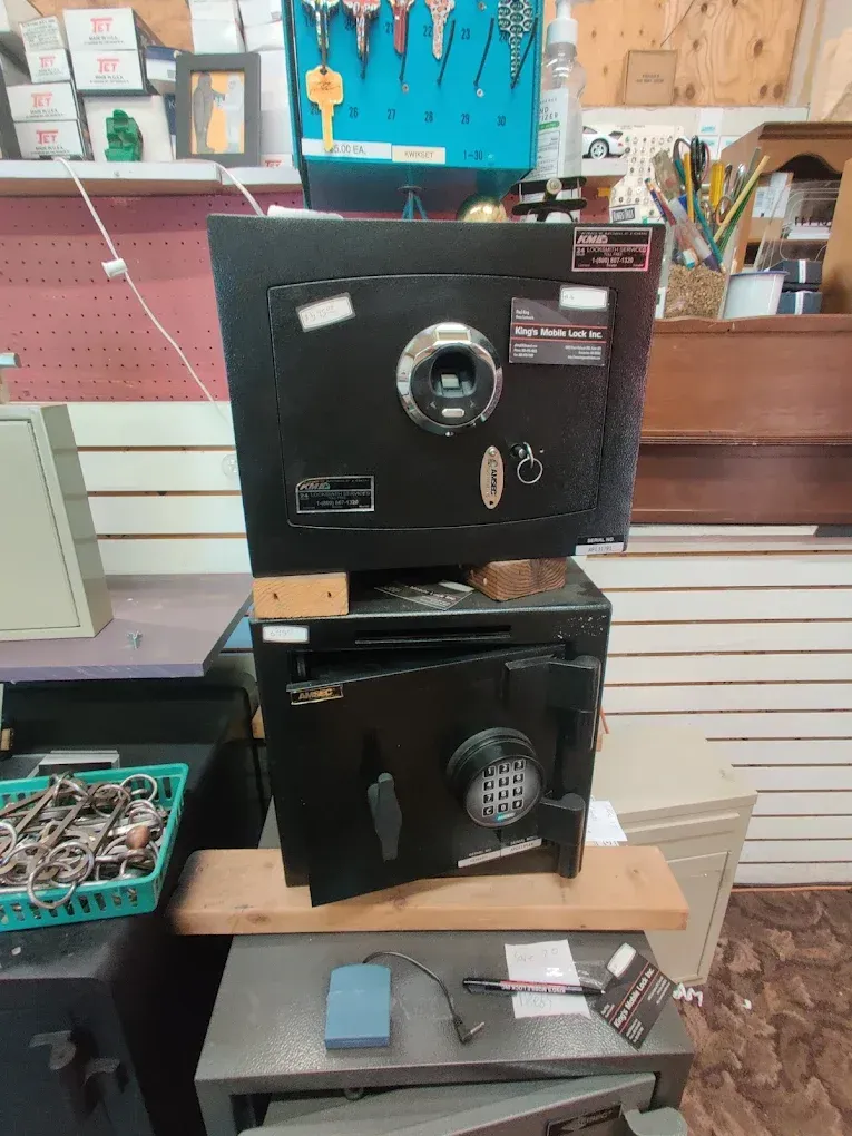 Two black safes stacked on a wooden shelf in a shop, one open.