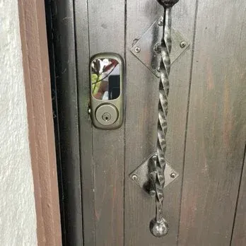 Wooden door with a shiny, twisted metal handle and a modern lock.