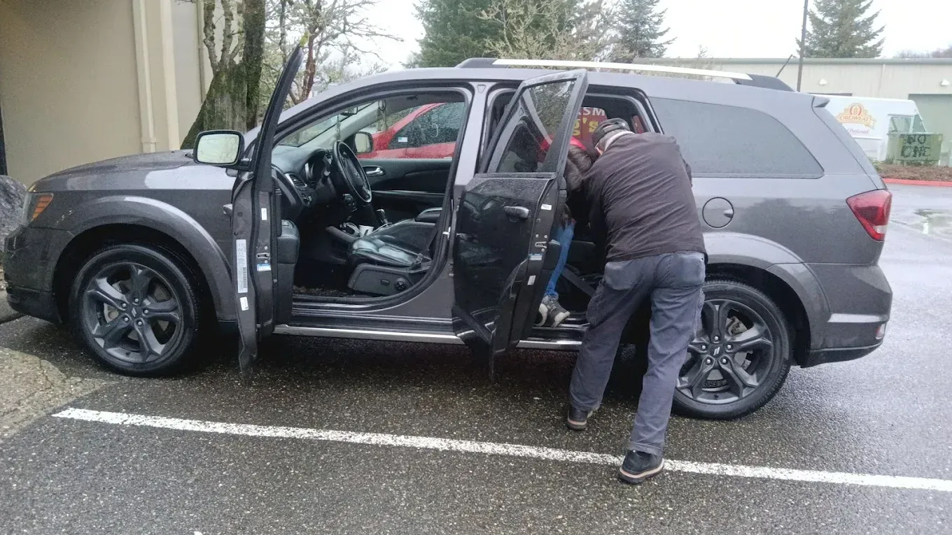 Man entering gray SUV with open doors in a parking lot.