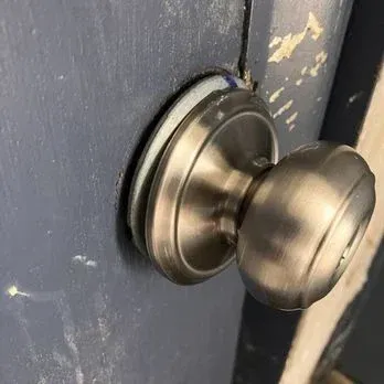 Silver doorknob on a dark blue door with chipping paint.