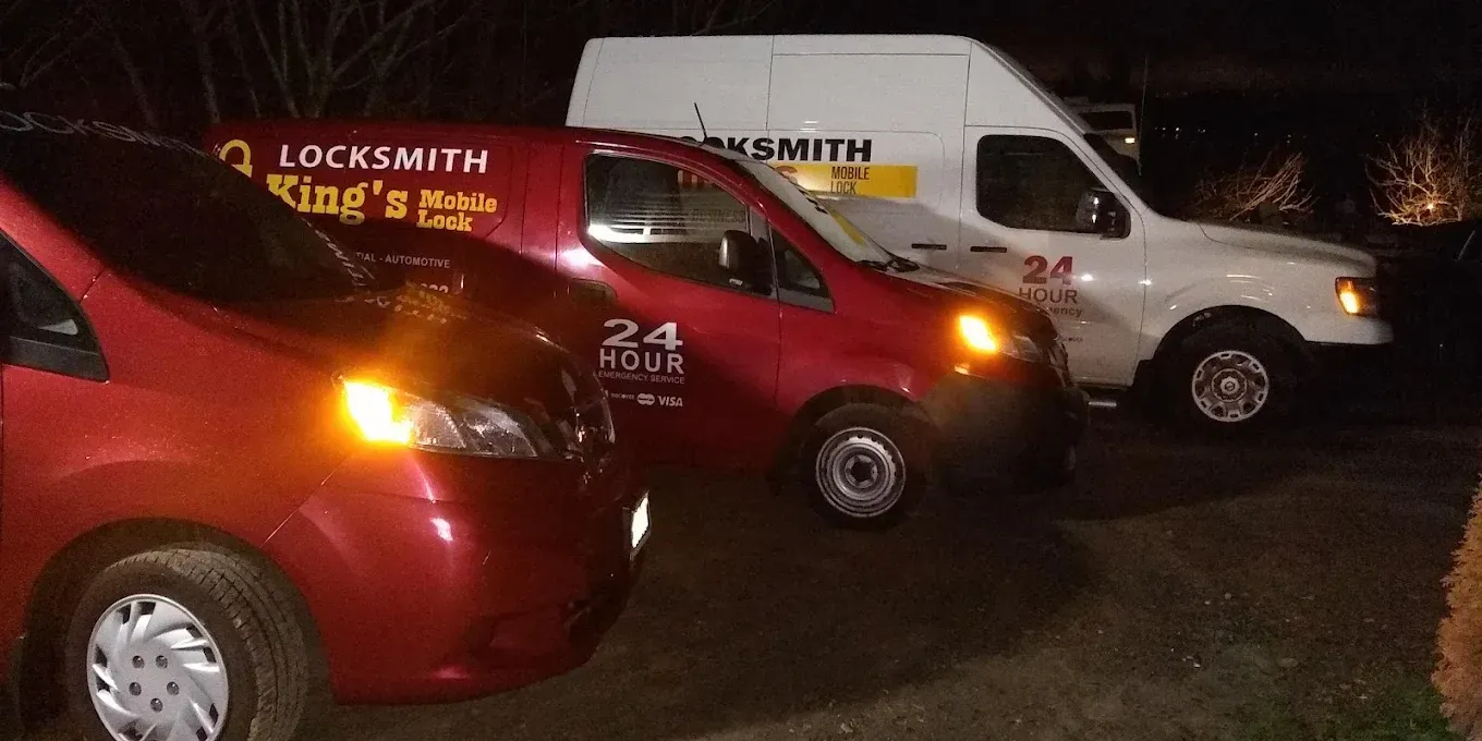 Three locksmith vans, two red, one white, parked at night.