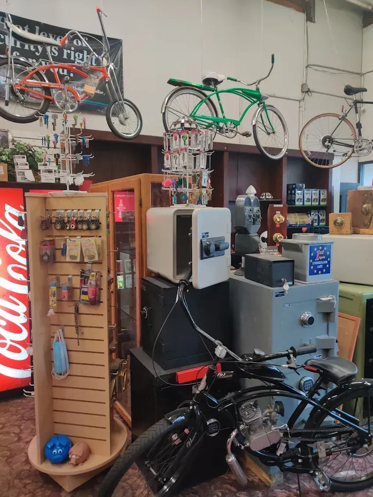 Store interior with bicycles and safes for sale. Includes a Coca-Cola sign and display cases.