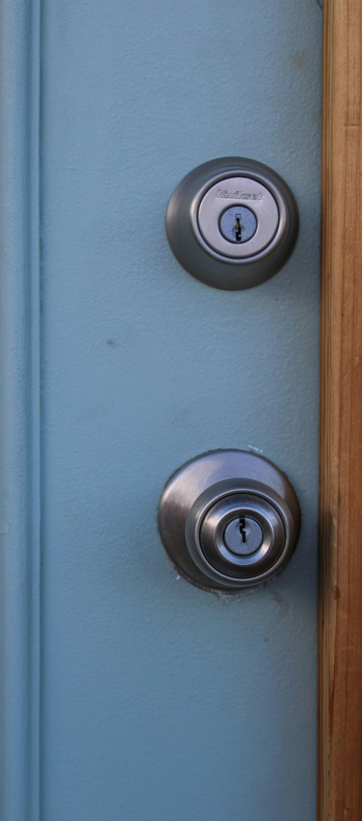 Two silver door locks on a light blue door