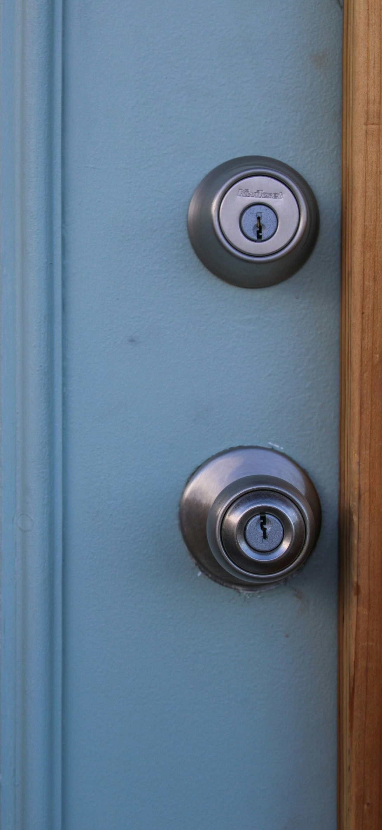 Two silver door locks on a light blue door