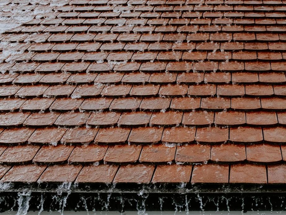 Rain is falling on a red tiled roof.