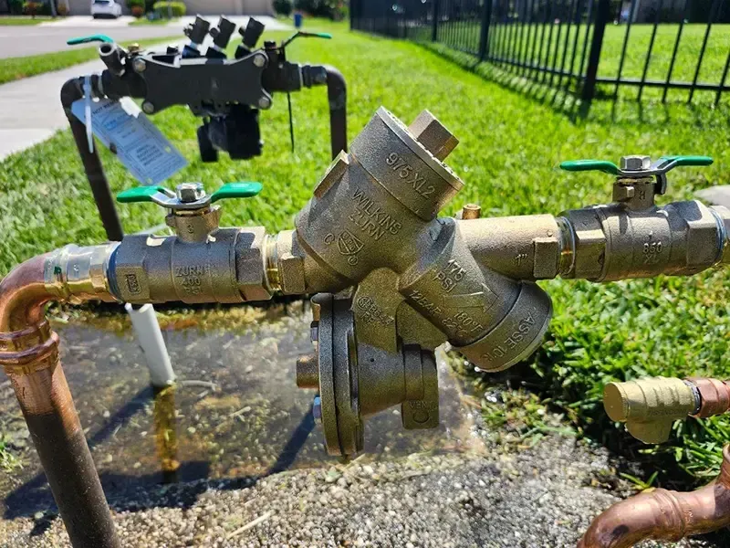 Outdoor irrigation system with brass pipes, valves, and water spray.