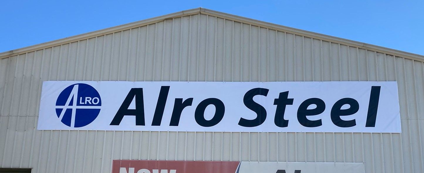 A large sign on the side of a building says alro steel