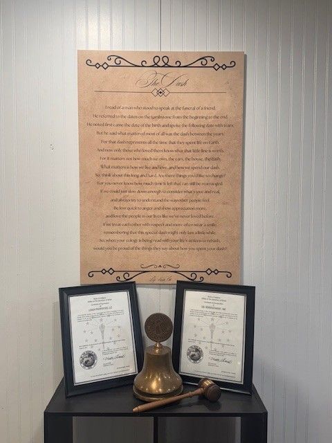 Three framed papers and a brass bell on a table