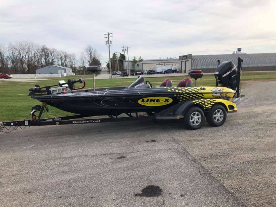 A black and yellow fishing boat is parked on a trailer.