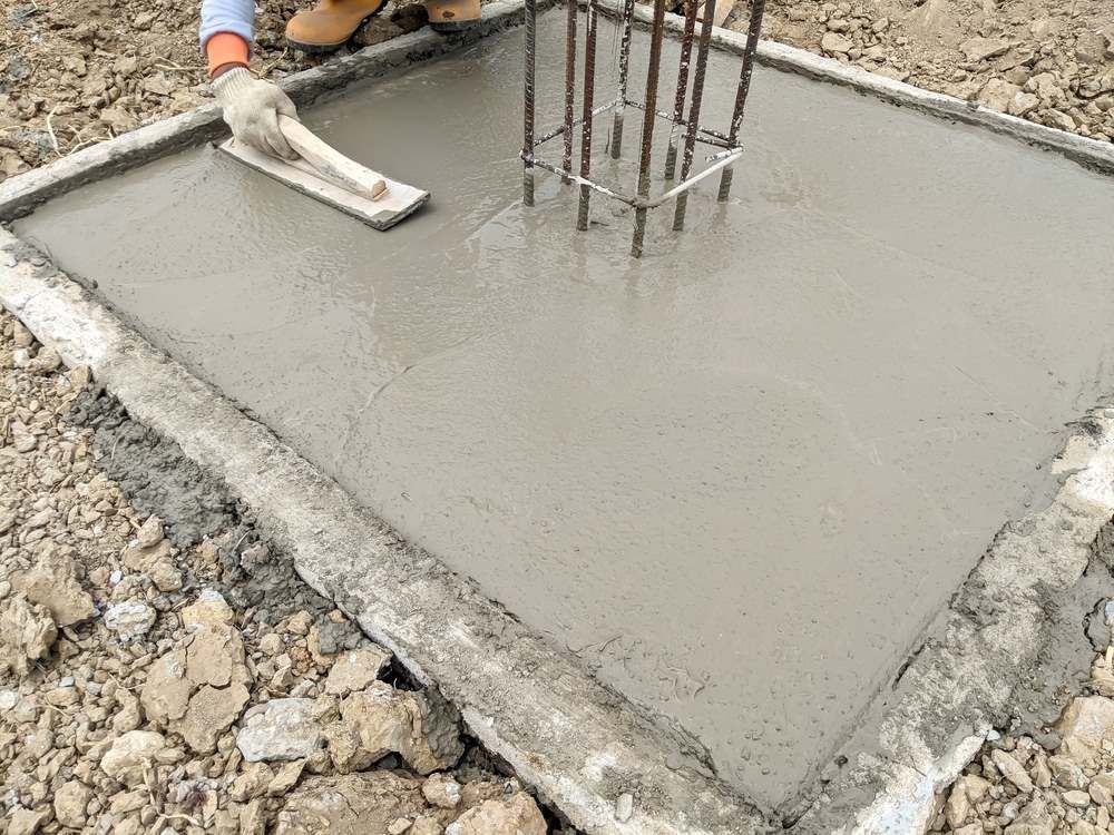 A Person Is Spreading Concrete On A Concrete Slab With A Trowel — C R Concreting in Miles, QLD