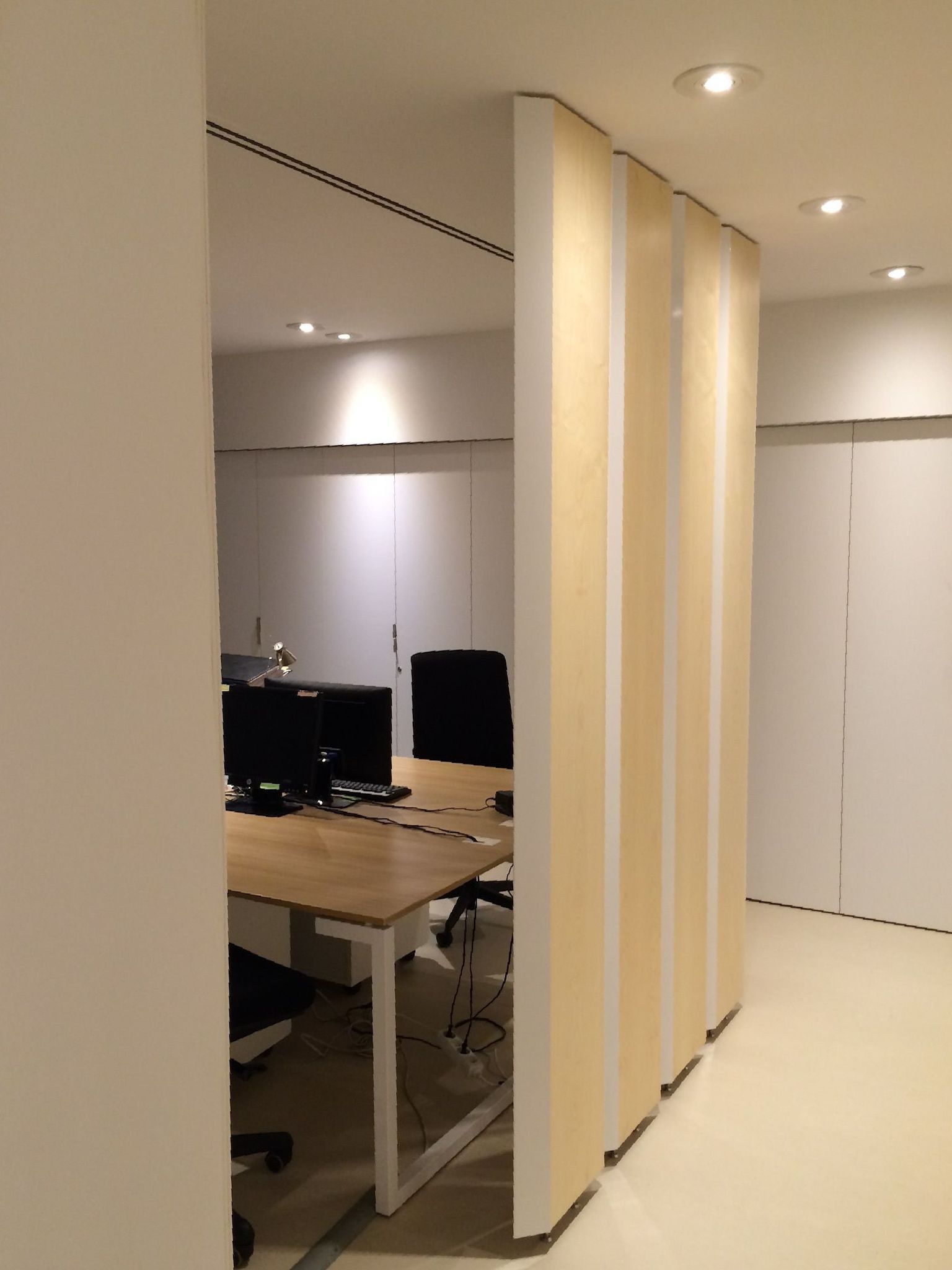 Un bureau avec une cloison en bois entre deux bureaux