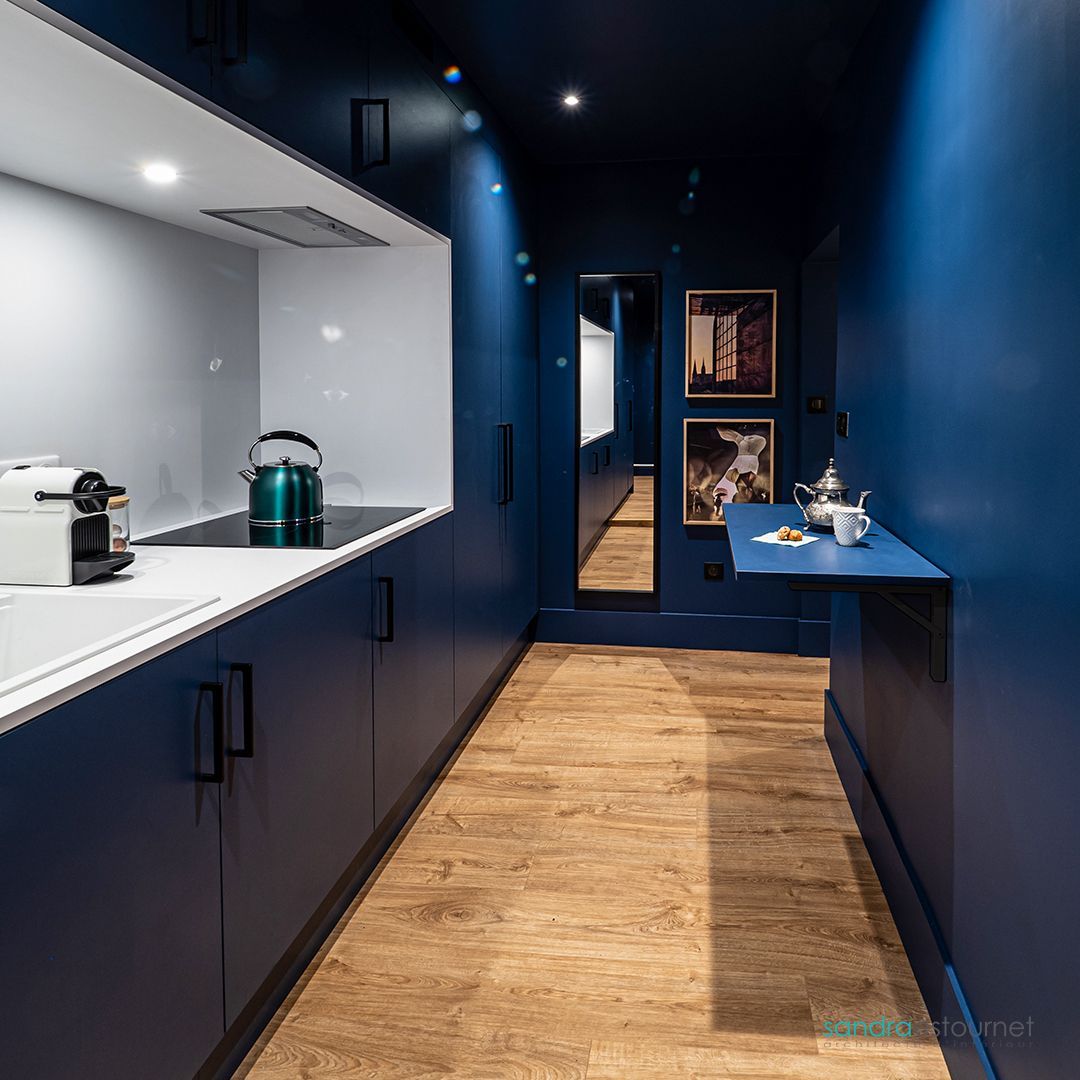 Une cuisine avec des murs bleus et du parquet