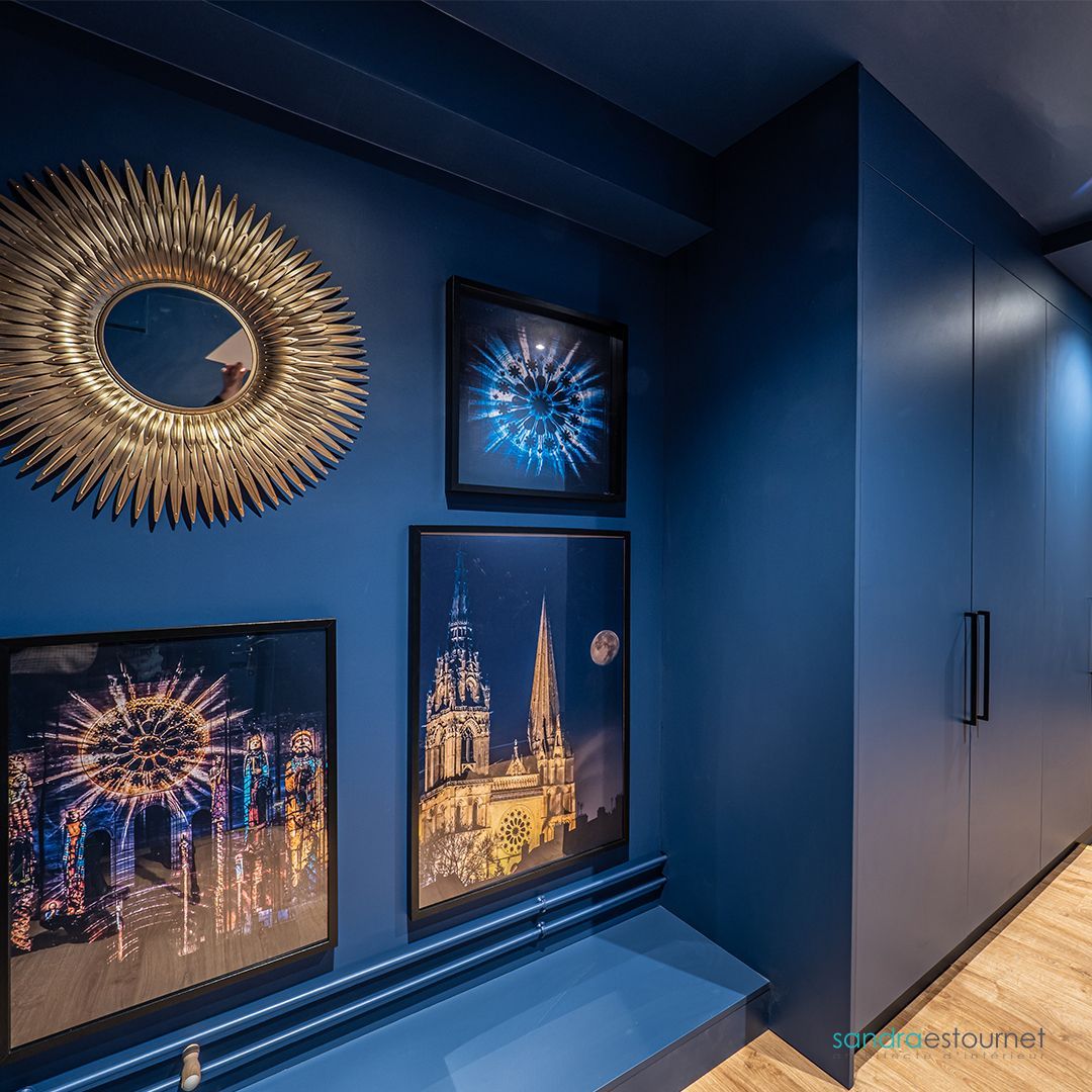 Un couloir avec des murs bleus et un miroir sur le mur.