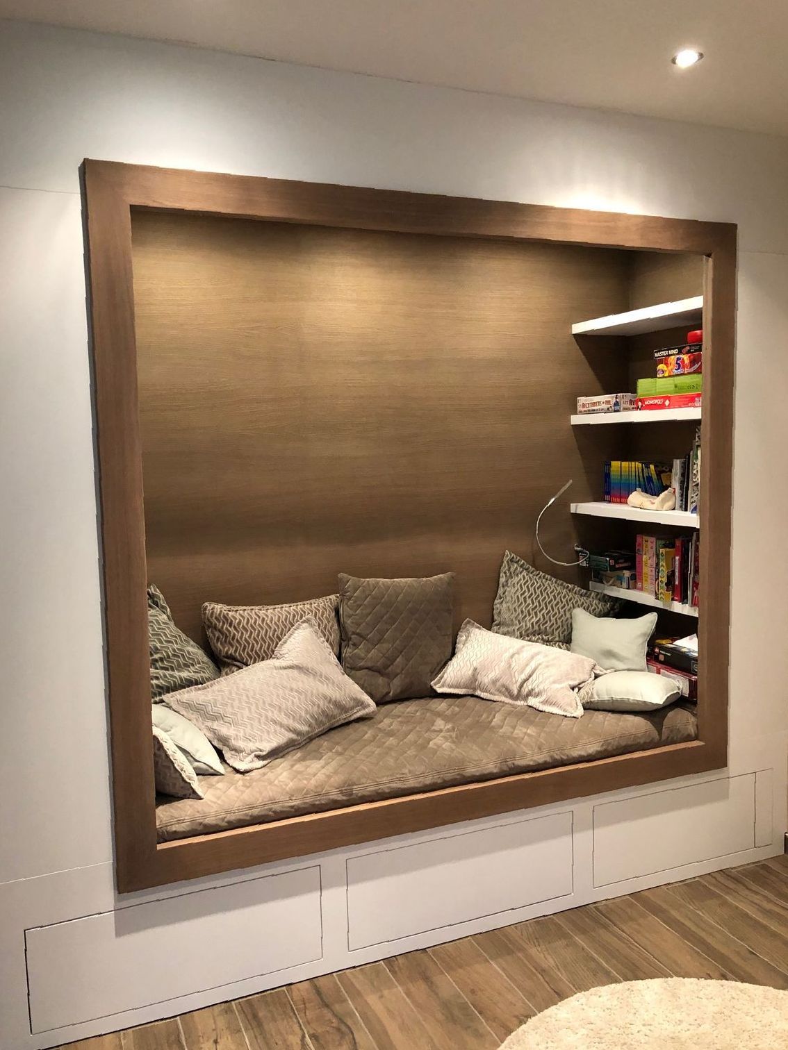 Un salon avec une banquette près de la fenêtre et une bibliothèque.