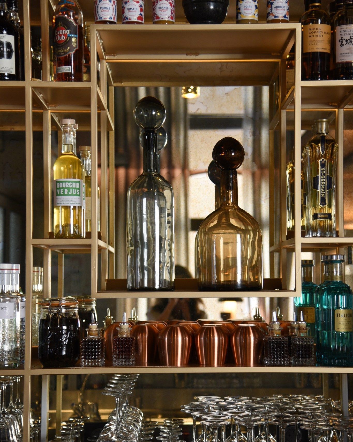 Une étagère pleine de bouteilles et de verres, dont un sur lequel est écrit « tequila »