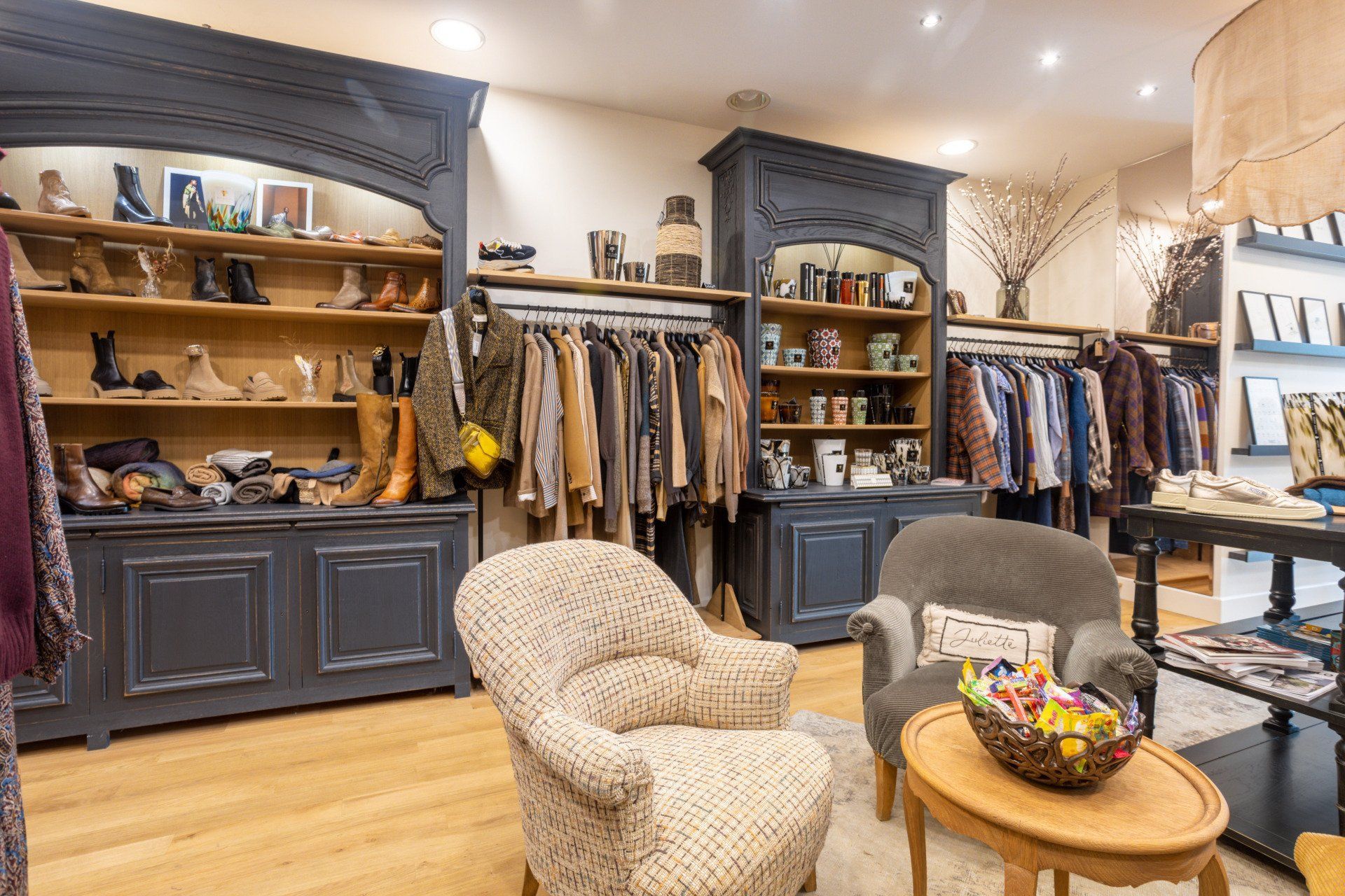 Il y a deux chaises et une table au milieu d'un magasin de vêtements.