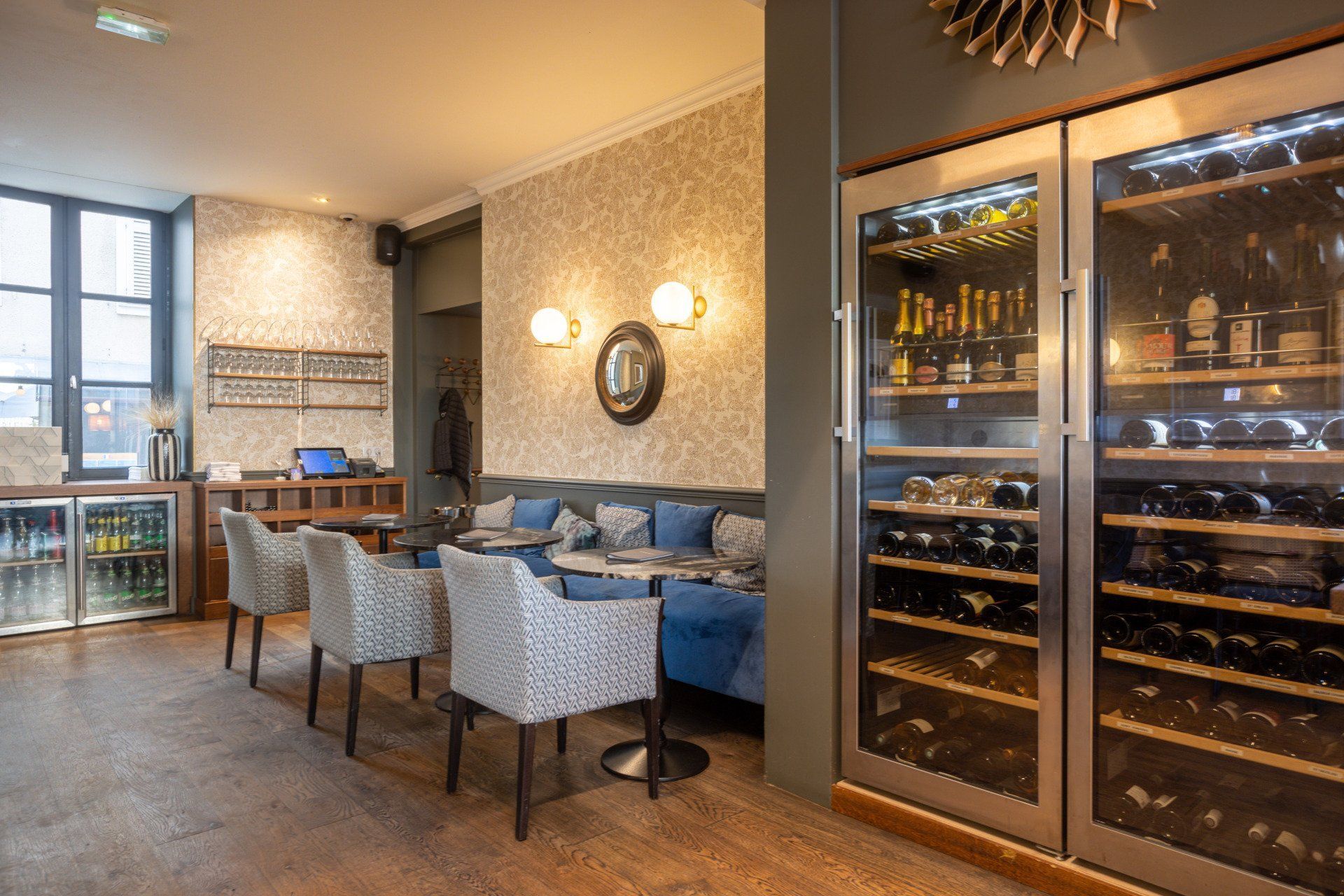 Un restaurant avec tables et chaises et un grand réfrigérateur à vin.