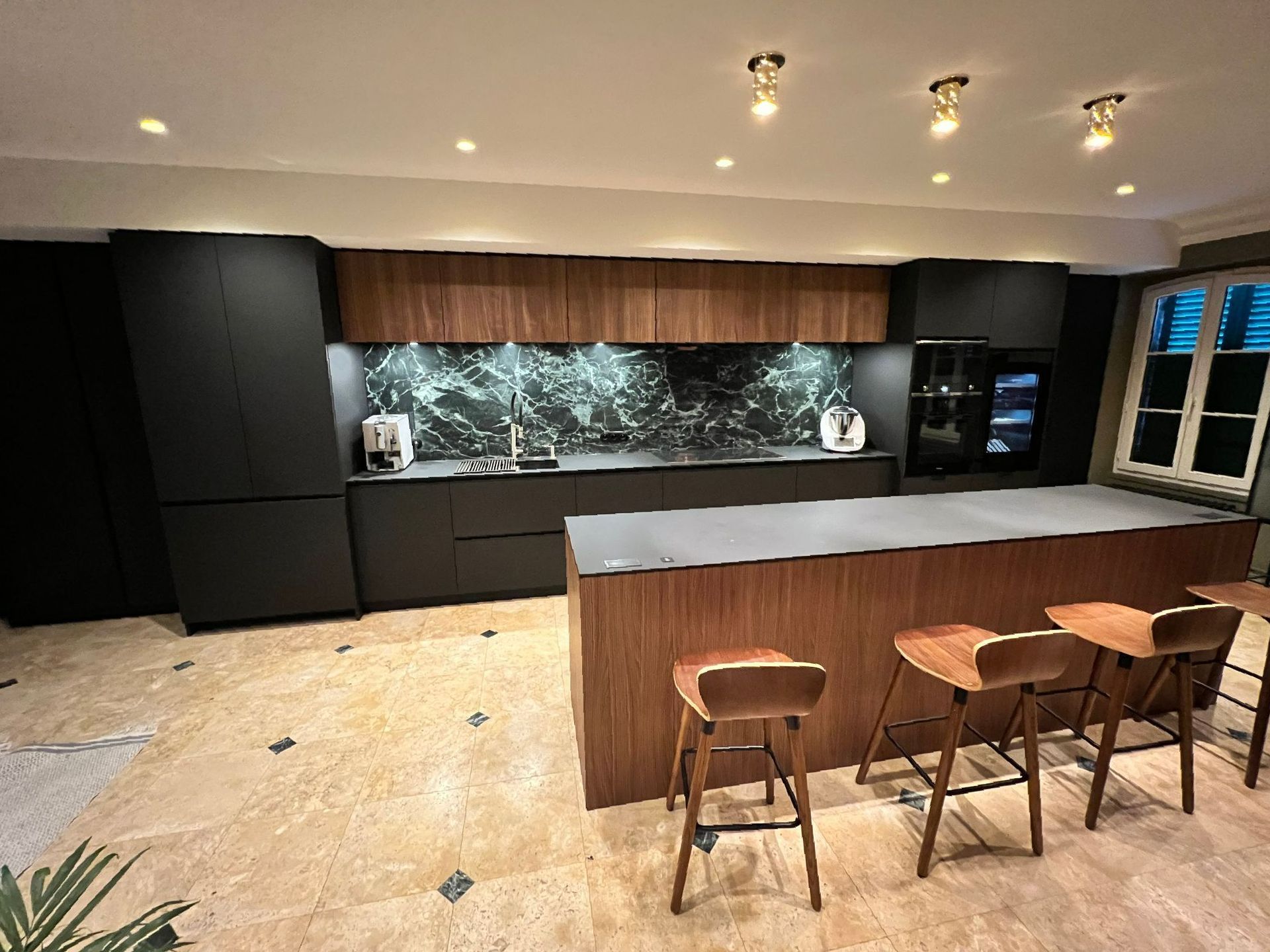 Une cuisine avec un grand îlot et des tabourets à l'intérieur.