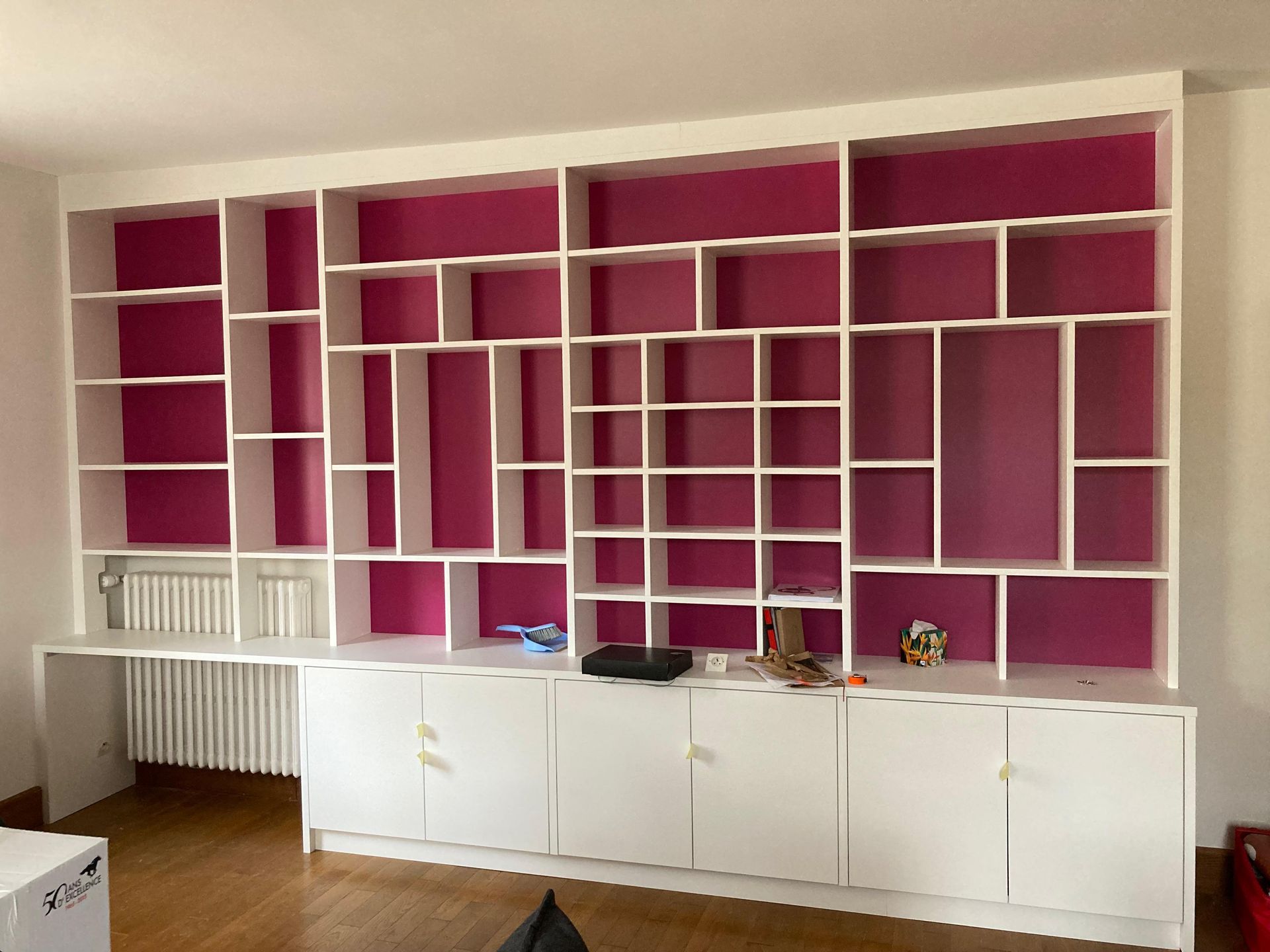 Une pièce avec beaucoup d'étagères et des murs roses