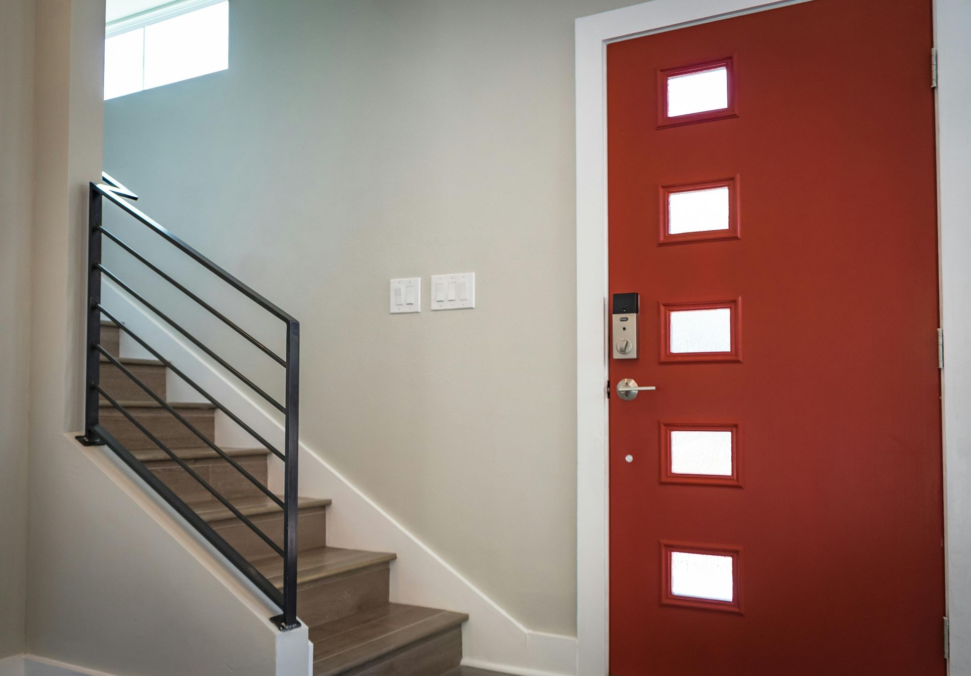 Escalier menant à une porte rouge avec des fenêtres carrées