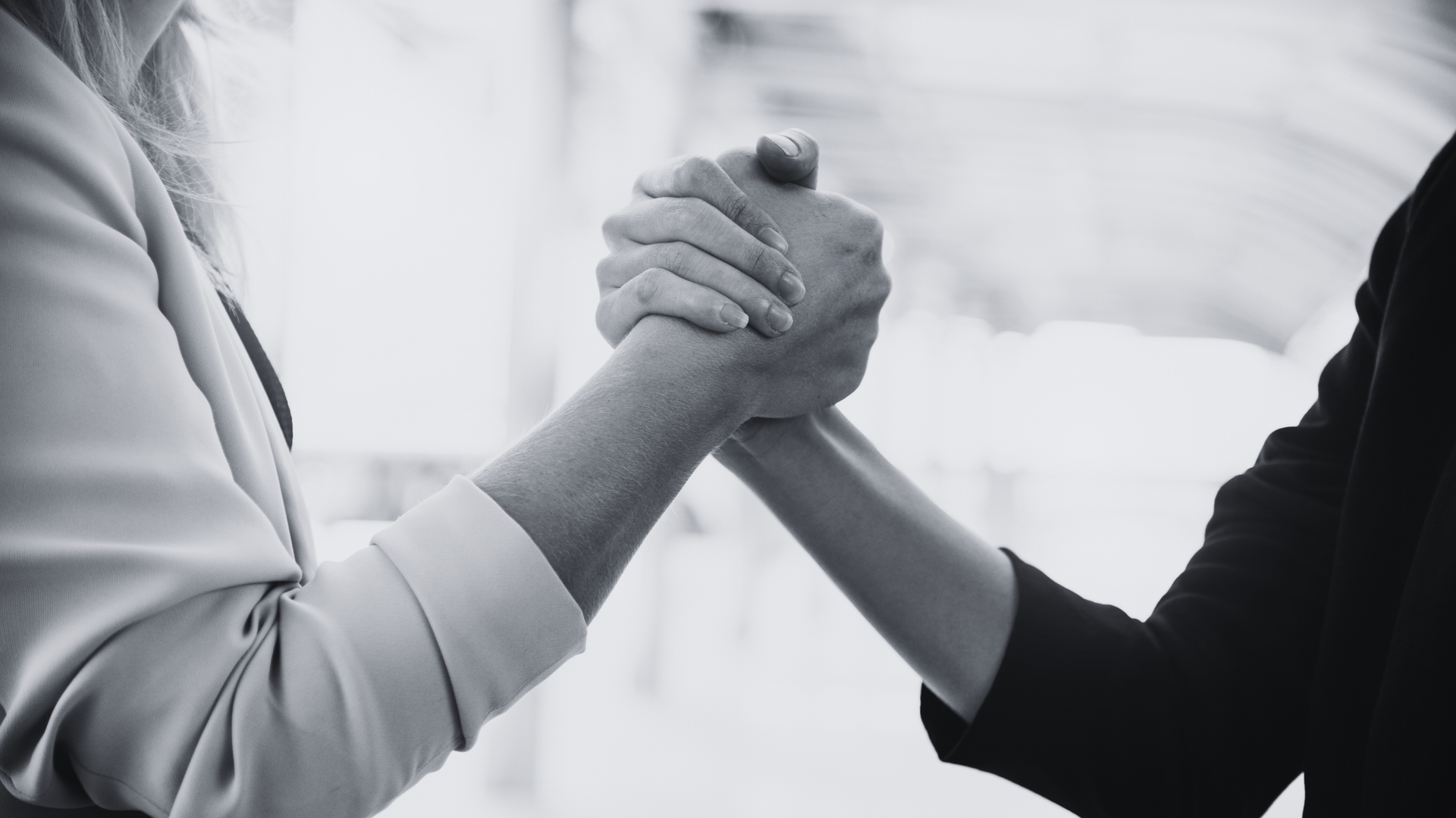 two women are shaking hands in a black and white photo .