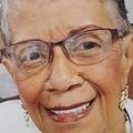 Close-up portrait of a smiling person wearing glasses and pearl earrings